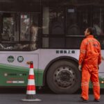 Een buschauffeur die een moderne bus bestuurt in de regio Utrecht, met op de achtergrond een stadslandschap.