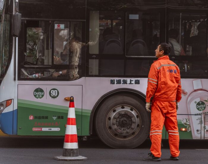 Een buschauffeur die een moderne bus bestuurt in de regio Utrecht, met op de achtergrond een stadslandschap.